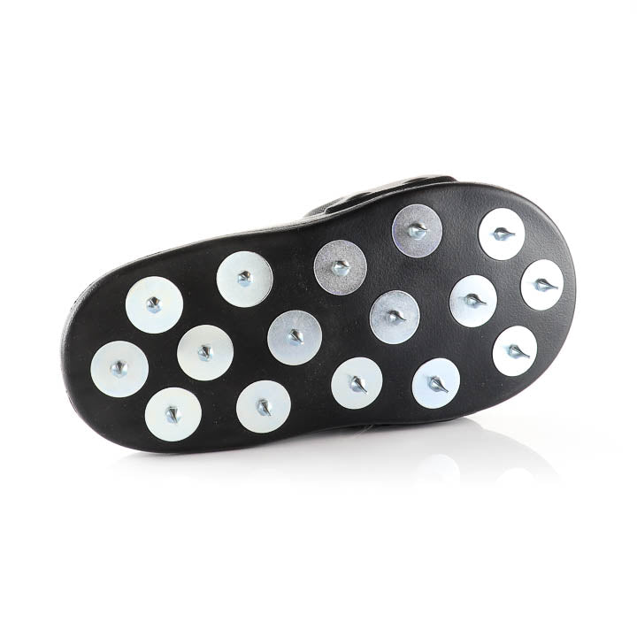 Bottom view of the black over-shoe sole displaying the evenly spaced array of metal spikes for epoxy installation.