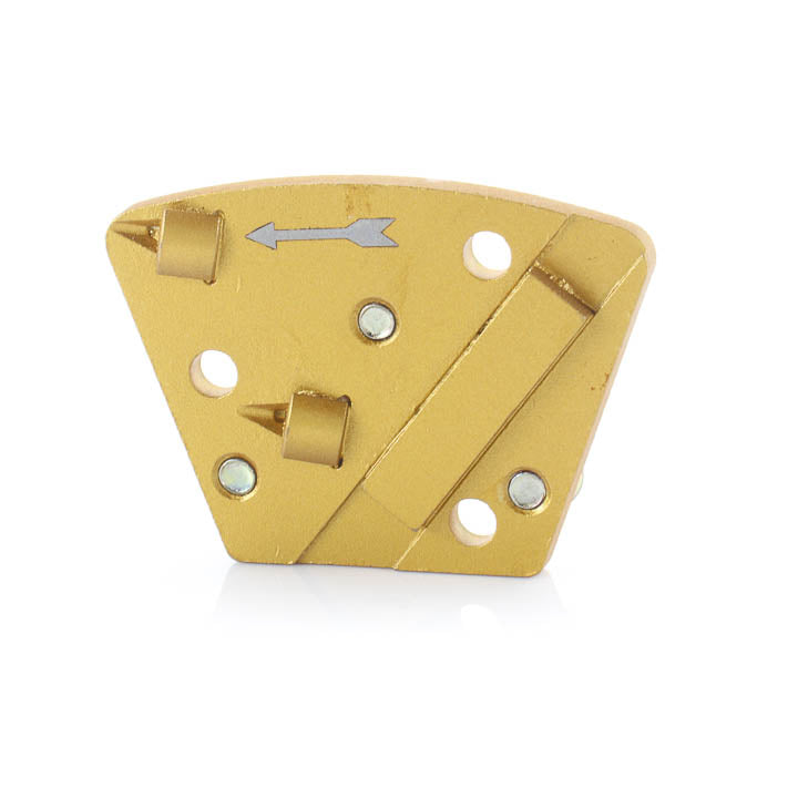 Gold-colored trapezoid PCD diamond grinding shoe for concrete floor grinders, featuring two pointed PCD segments, one diamond bar, a left-facing directional arrow, and three countersunk mounting holes on a white background.