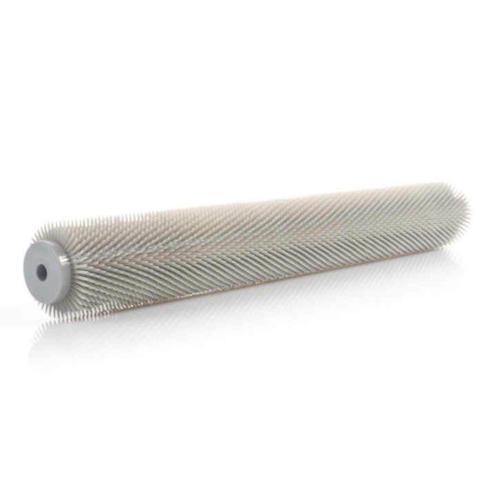 A side angle view of the gray cylindrical Midwest Rake 18-inch spiked roller with 0.5-inch plastic spikes, resting on a white surface.
